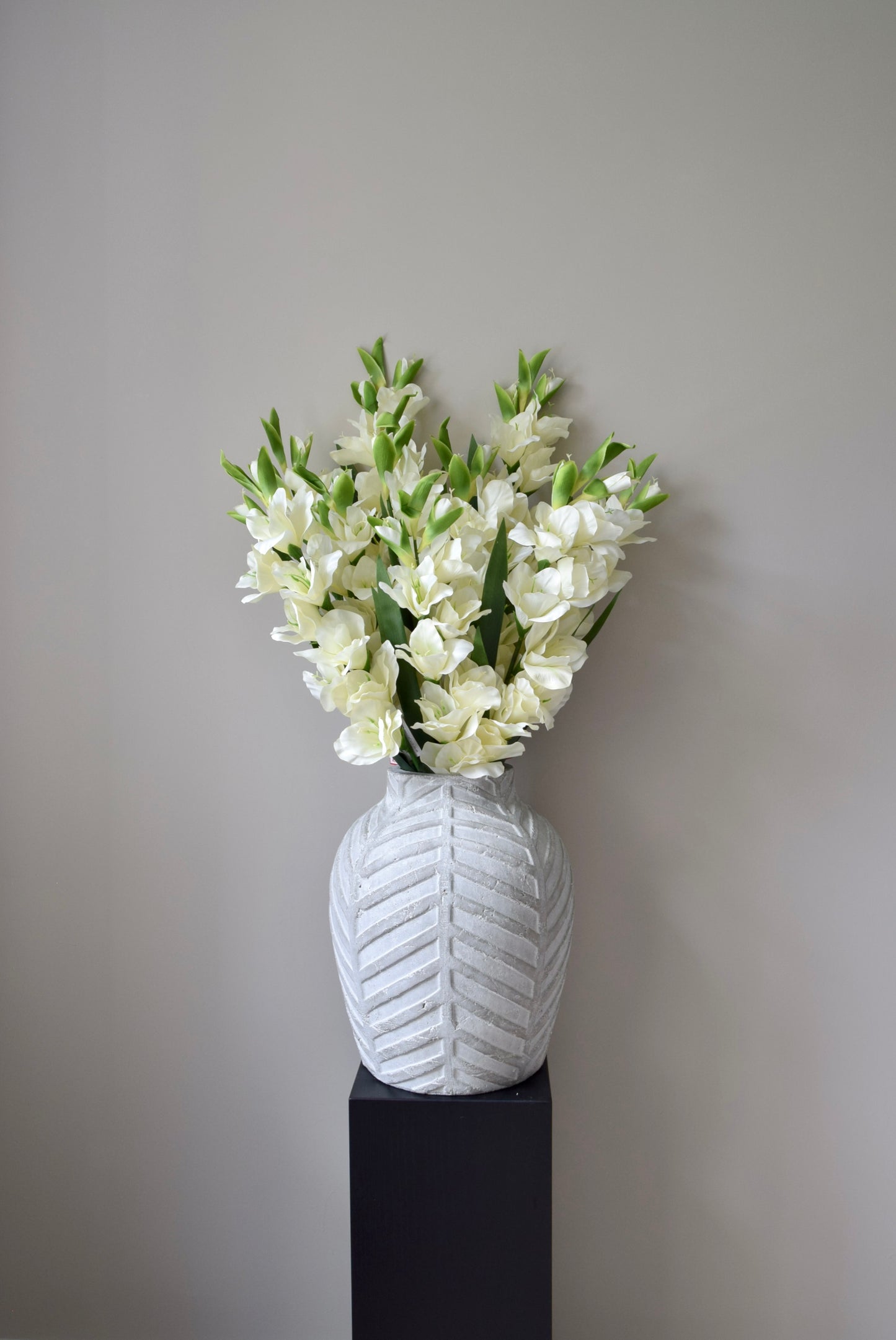 White textured vase with a bouquet of white flowers on a plain background