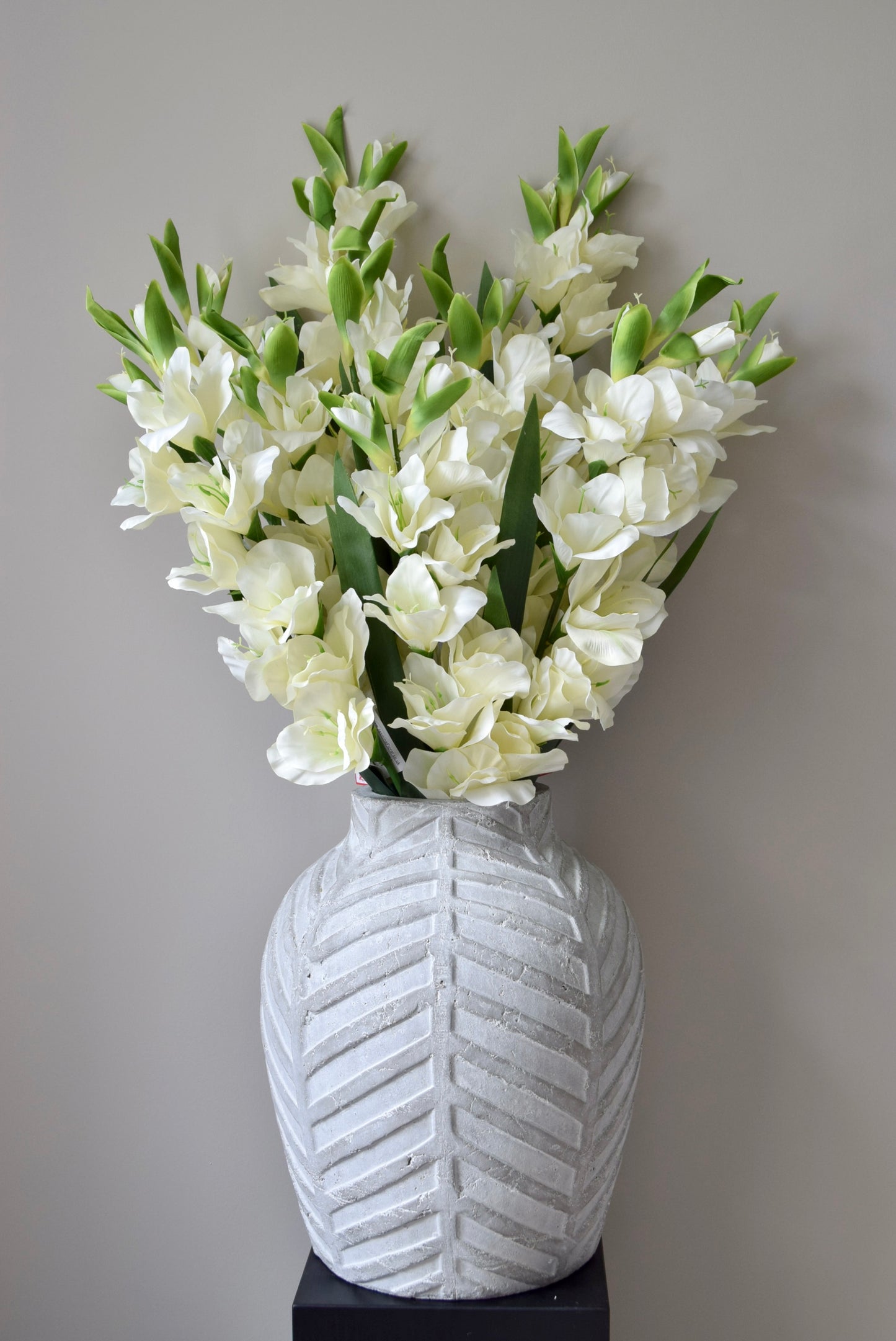 White flowers in a textured white vase against a neutral background