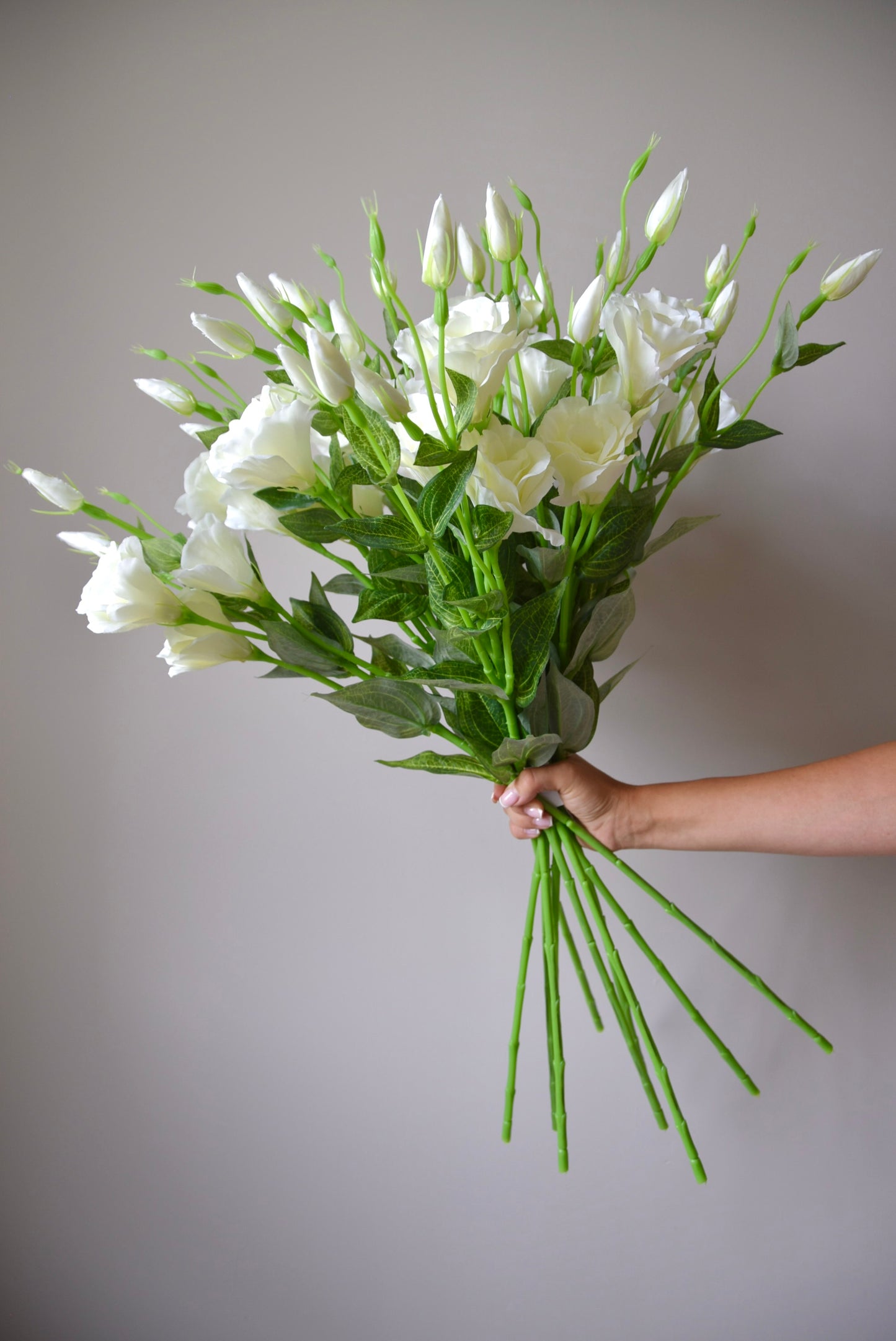 Bouquet of white flowers held against a plain background