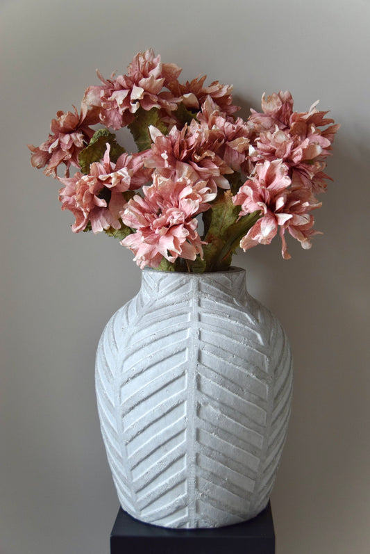 White textured vase with pink flowers against a plain background