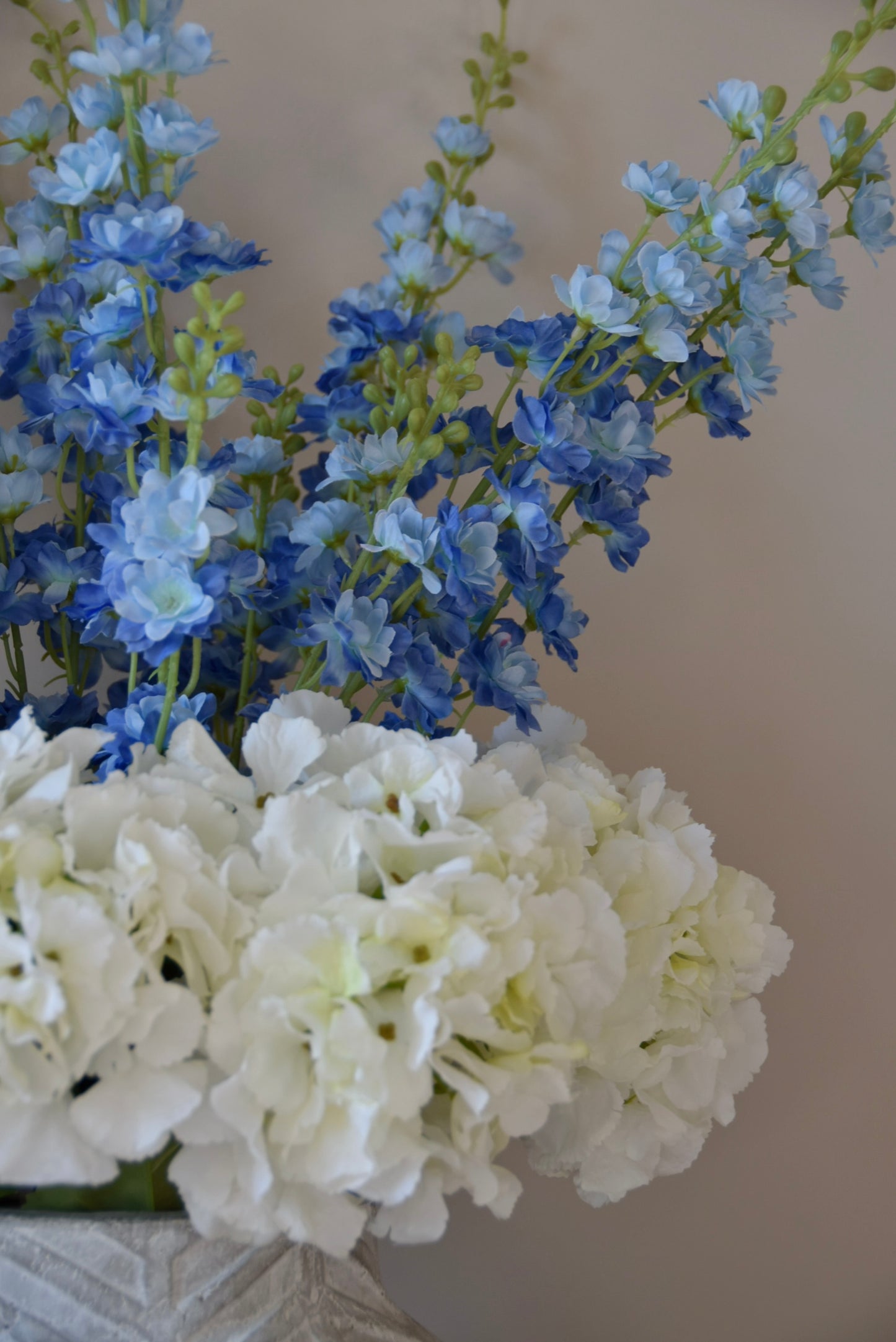 Close up of artificial white hydrangea and blue delphinium flower arrangement.