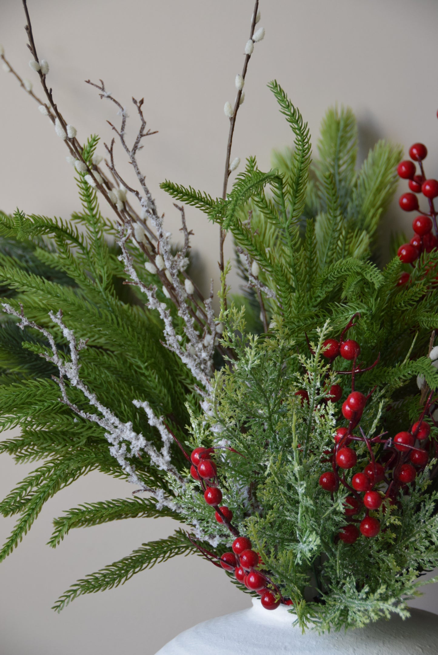 Decorative wreath with greenery and red berries on a plain background