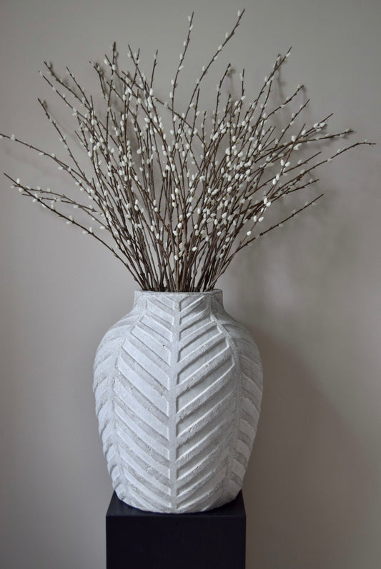 White textured vase with decorative branches on a plain background