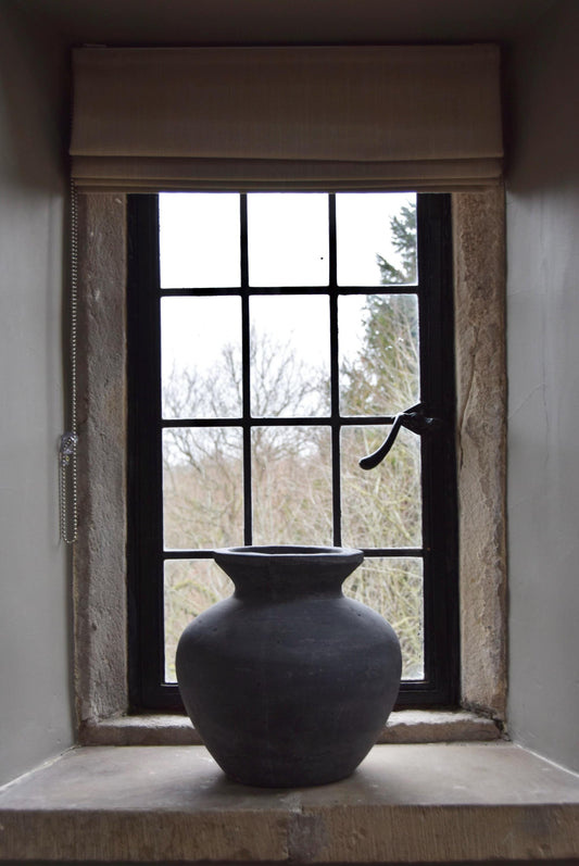 Grey stone vase placed on a stone windowsill in a country style house for home decor