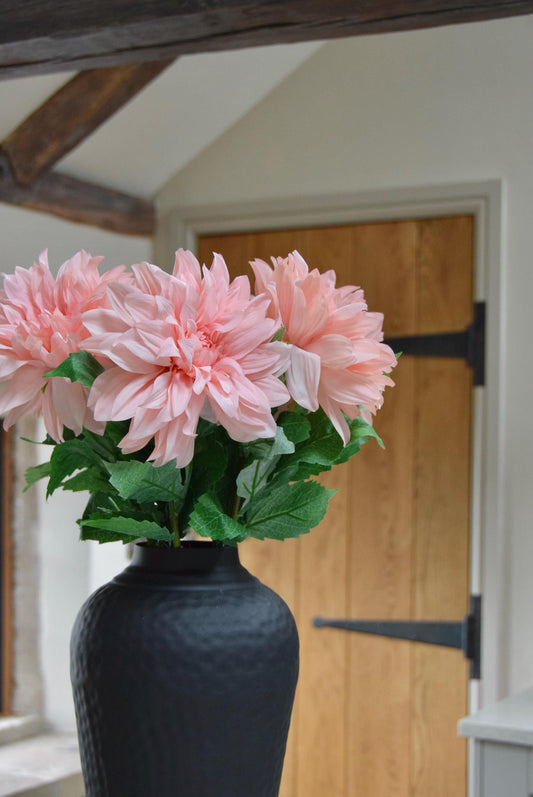 Tall black vase placed on a kitchen countertop with a bunch of pink monarch dahlia stems. Displayed in a country style kitchen for home decor.