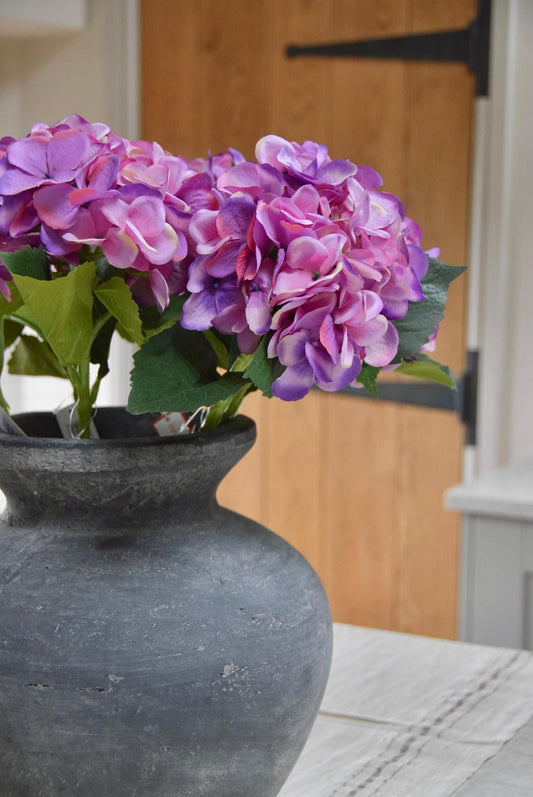 Grey vase placed on a kitchen counter top with purple hydrangeas arranged for home decor