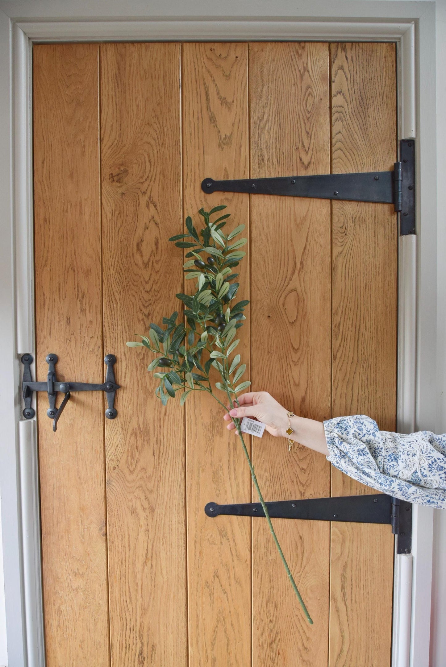 Artificial olive branch stem displayed against a country style wooden door.
