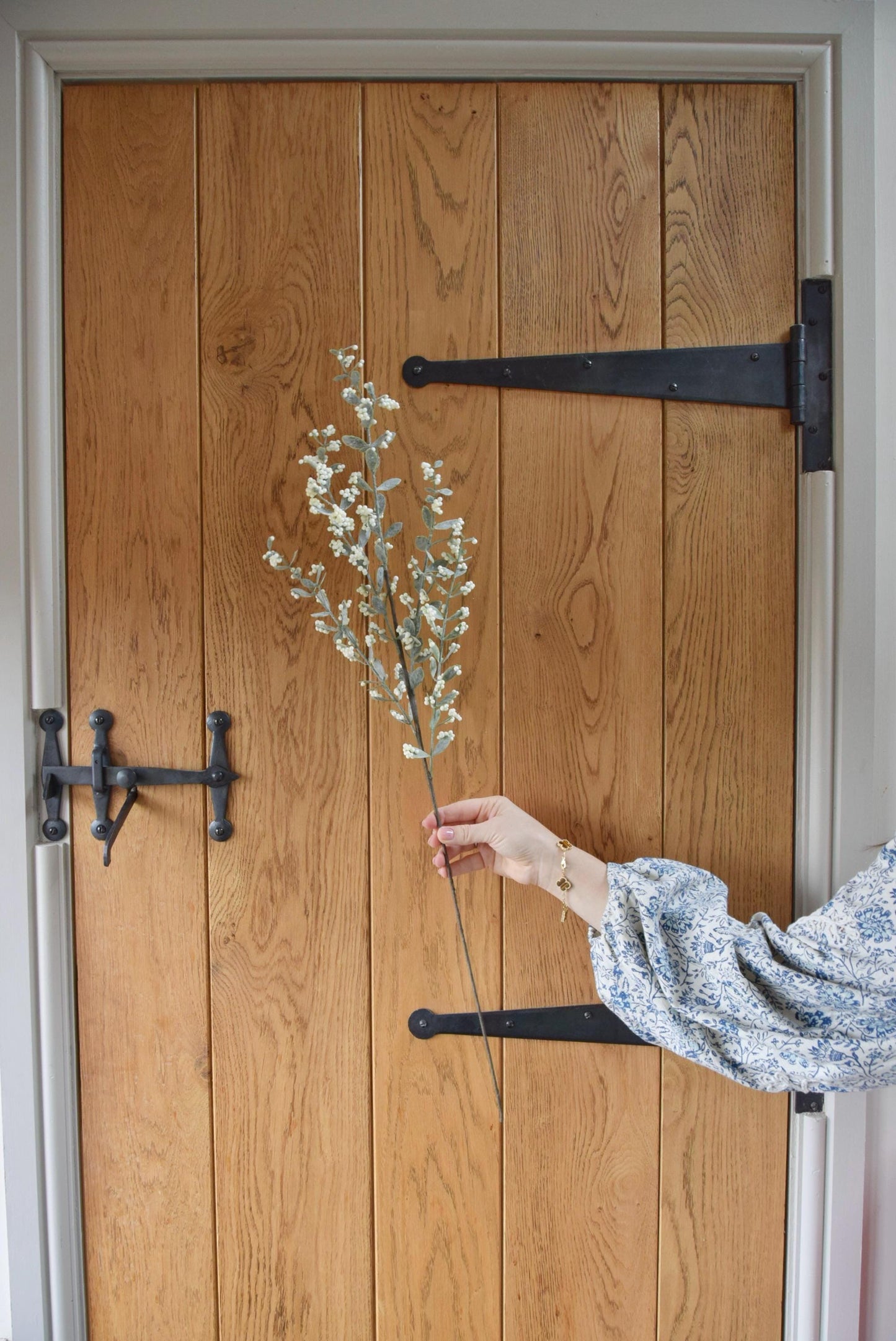 Artificial berry leaf stem displayed against a country style wooden door.
