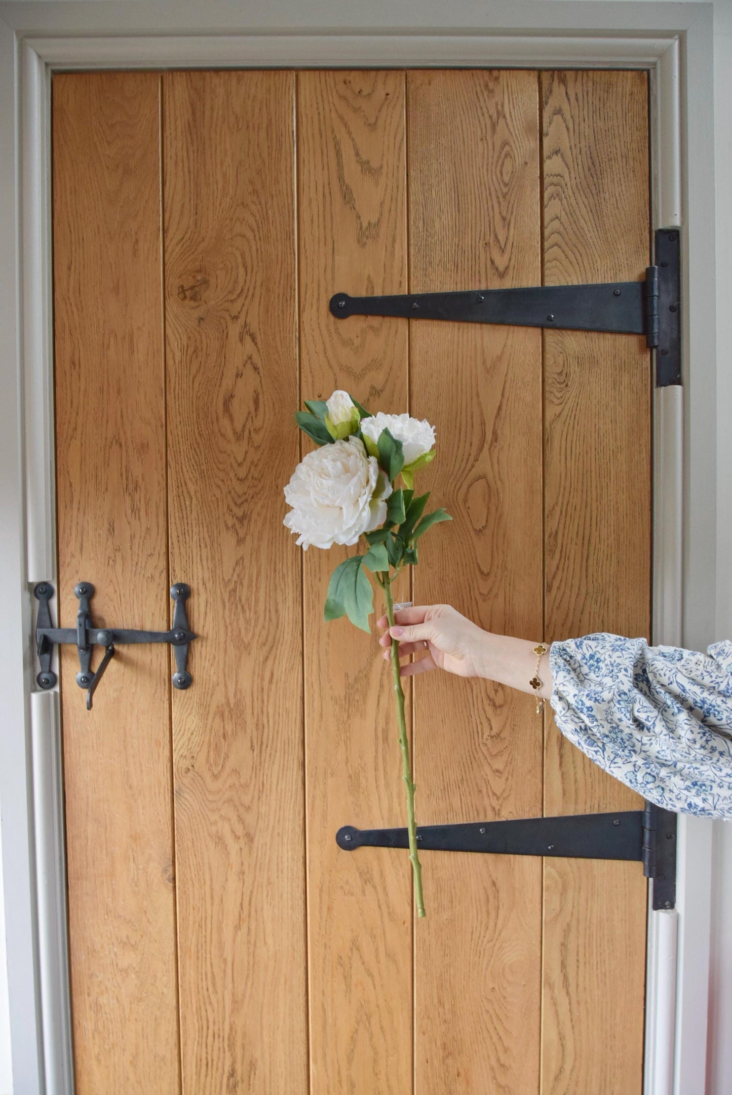 Artificial cream peony displayed against a country style wooden door.