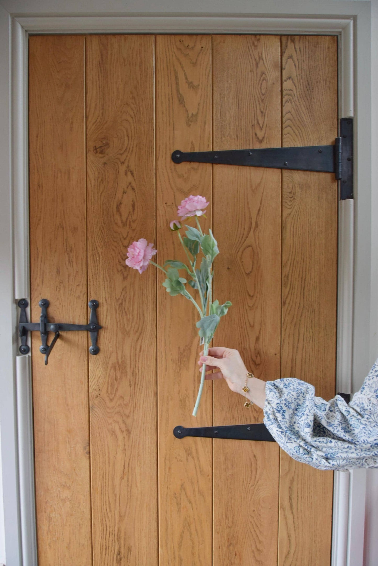 Pink ranunculus displayed against a country style wooden door.