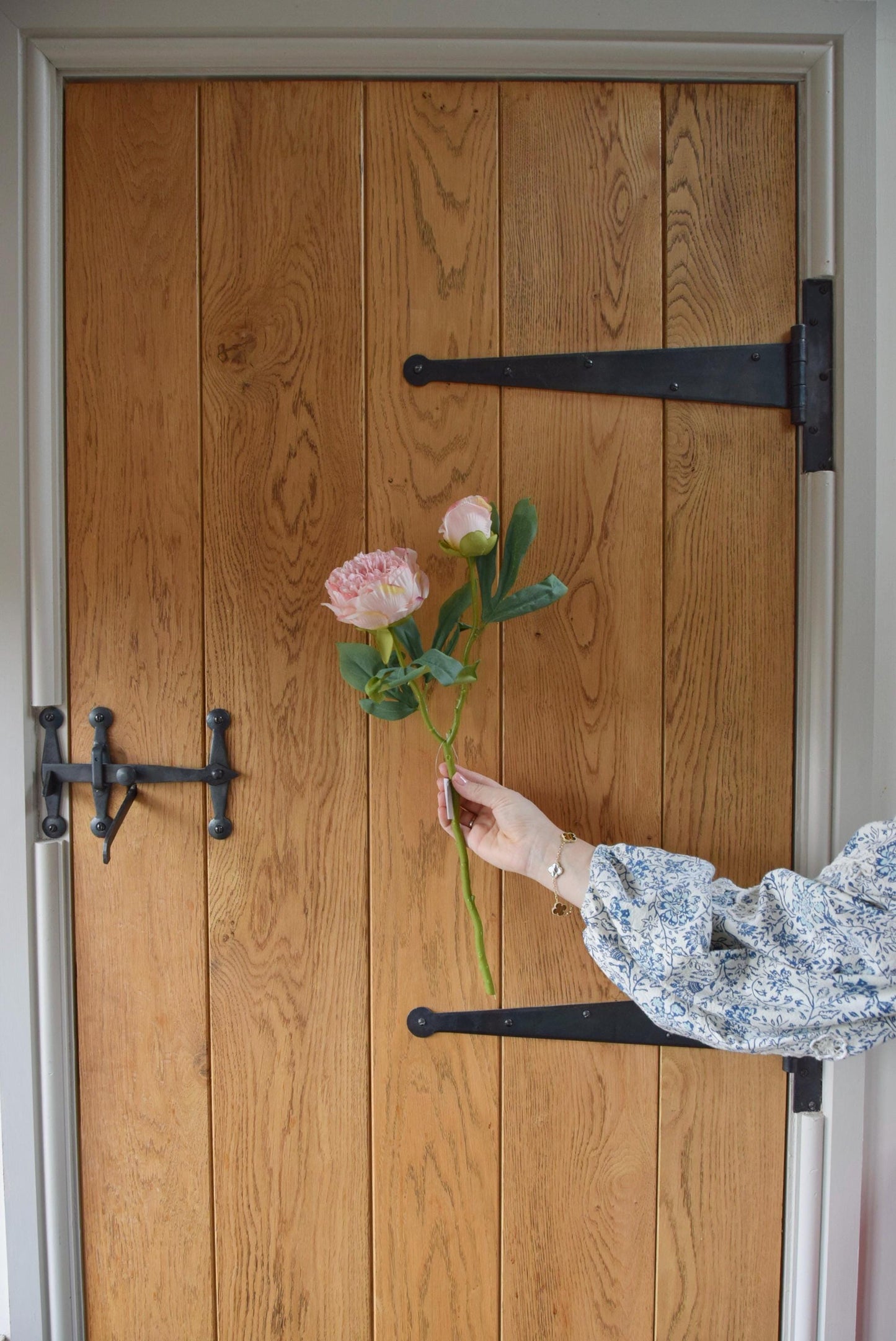 Pale pink peony displayed against a country style wooden door