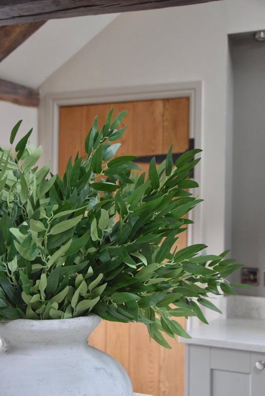 Stone vase on kitchen countertop featuring green foliage leaf stems in a country style kitchen for home decor.