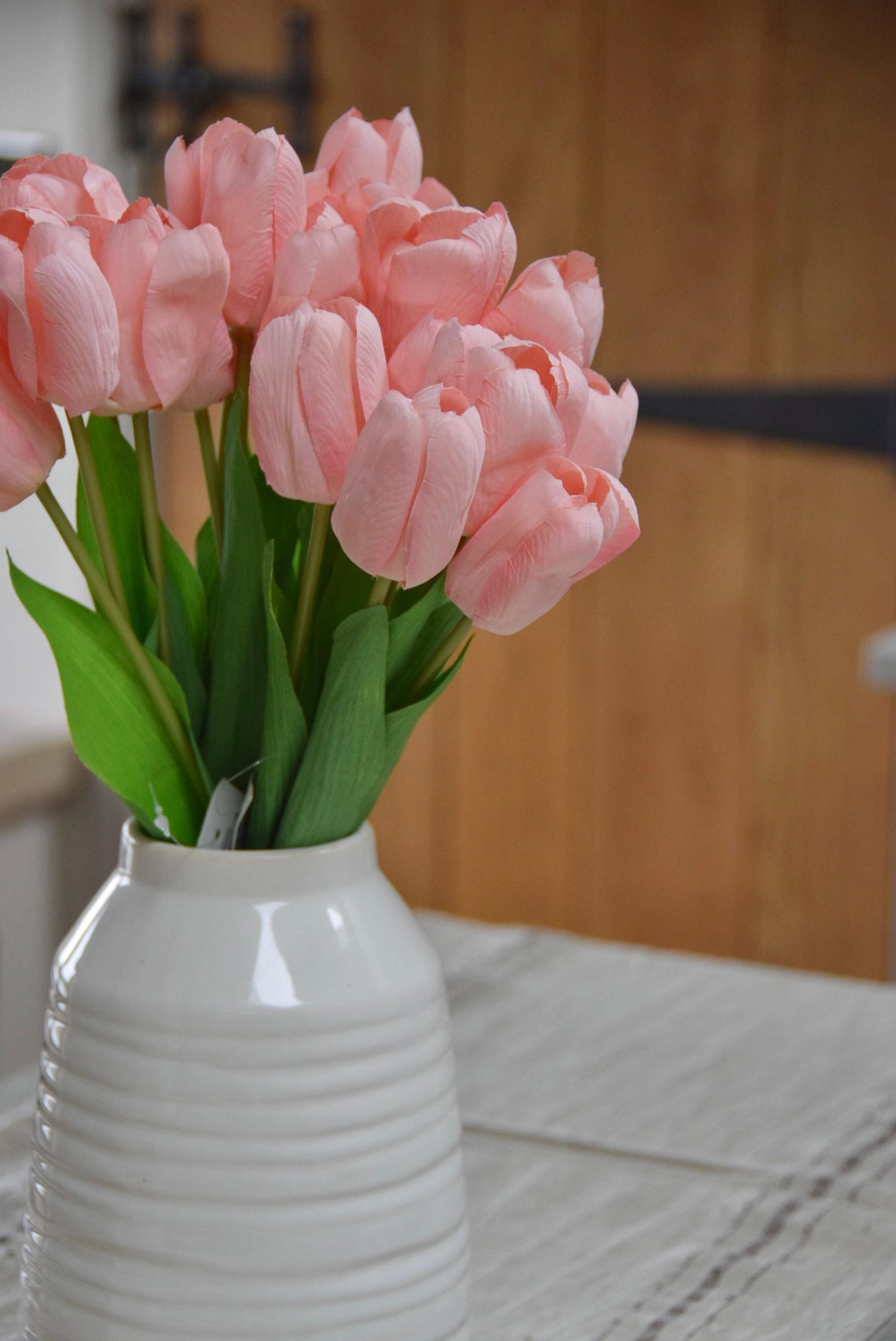 Pink tulips set in a cream vase on a kitchen counter top in a country style kitchen for home decor