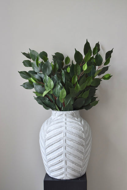 White textured vase with green leaves on a plain background