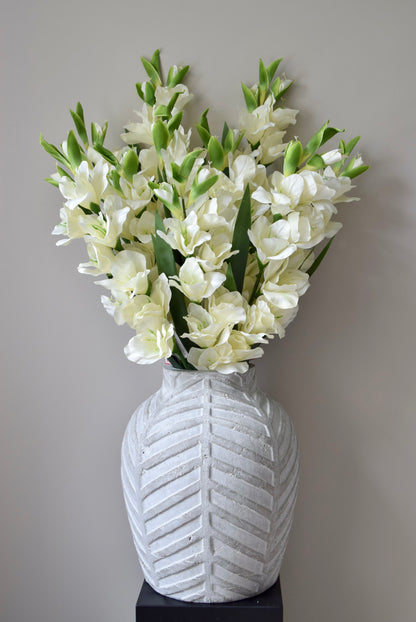White flowers in a textured white vase against a neutral background