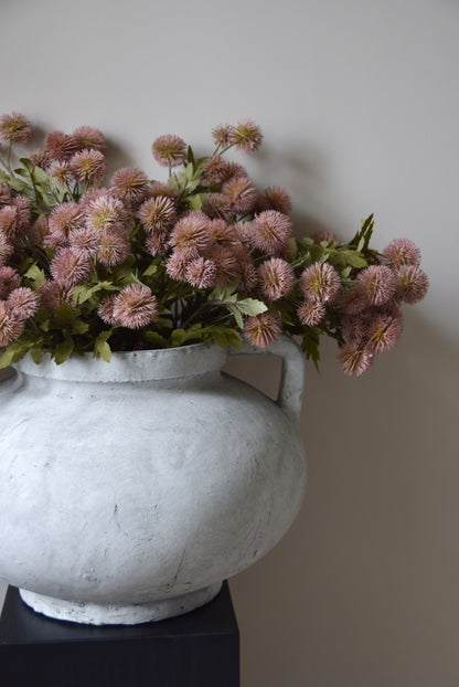 Decorative vase with pink flowers against a plain wall