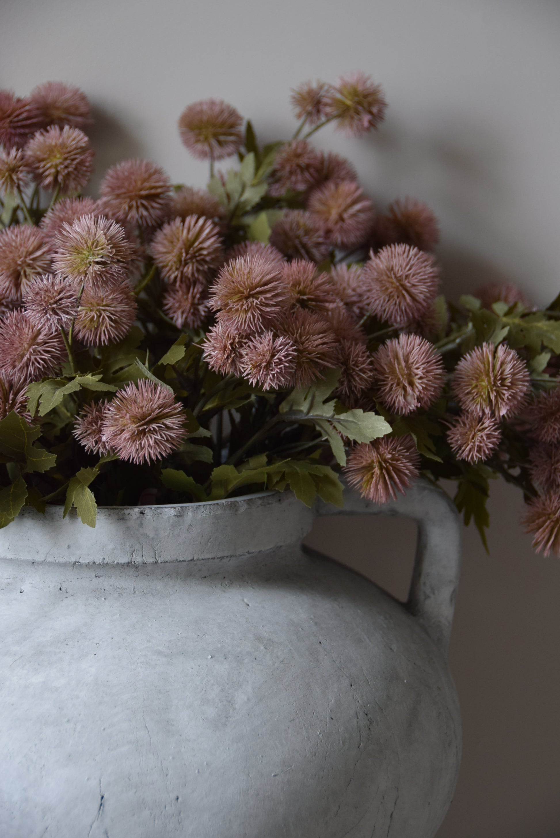Pink flowers with green leaves against a neutral background