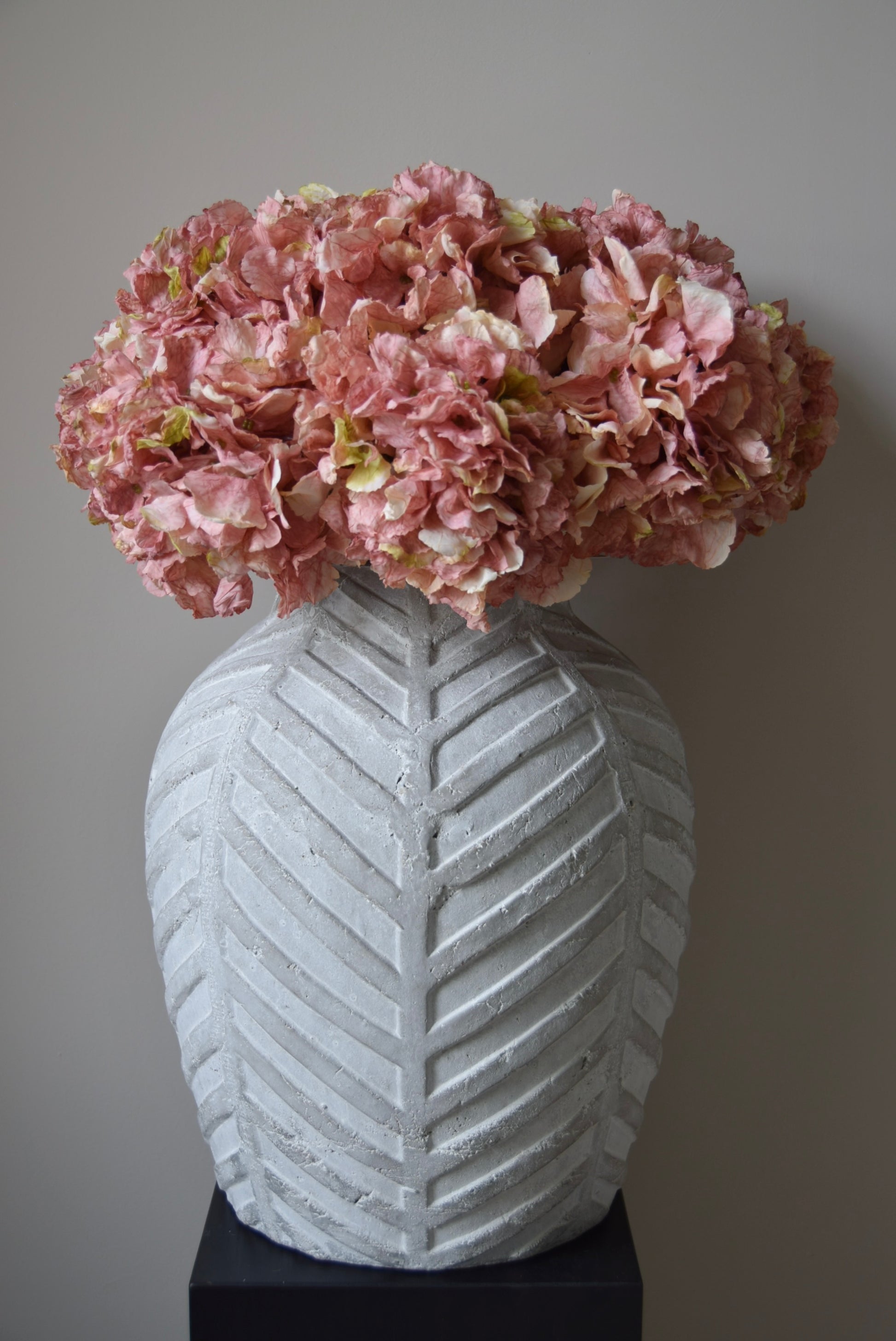 White textured vase with pink flowers against a gray background