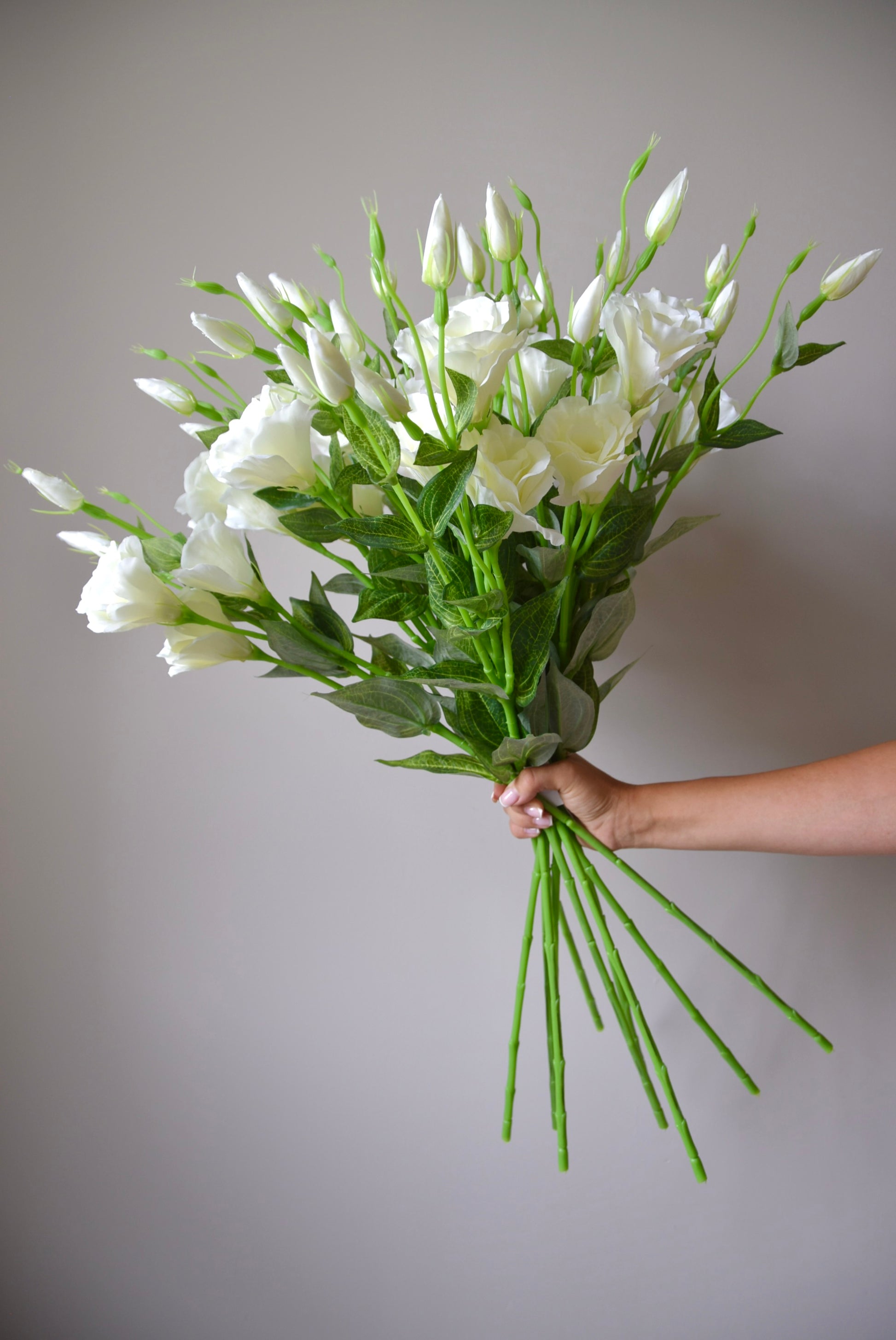 Bouquet of white flowers held against a plain background