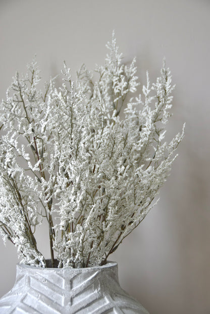 Decorative vase with white dried plants against a plain background