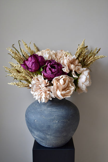 Decorative vase with purple and beige flowers on a gray background