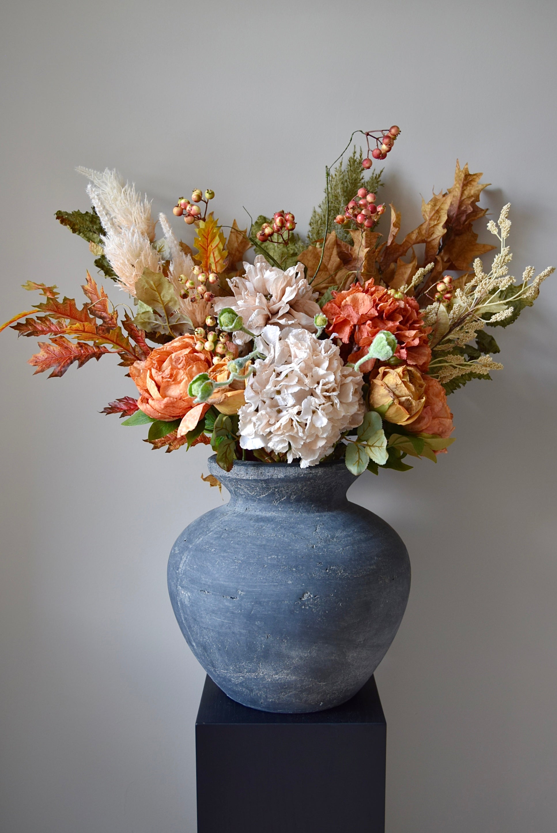 Decorative floral arrangement in a textured grey vase against a plain background