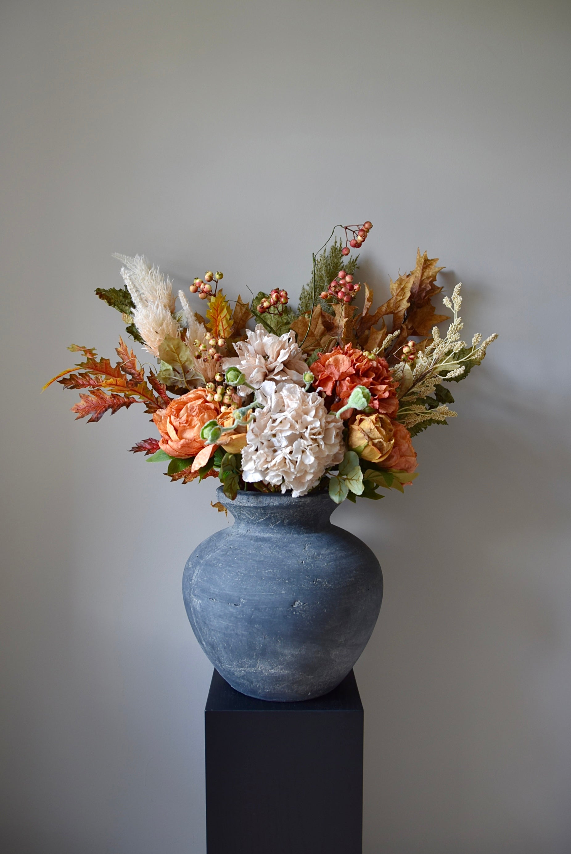 Decorative floral arrangement in a grey vase against a plain background