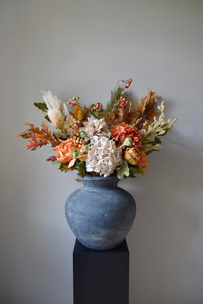 Decorative floral arrangement in a grey vase against a plain background