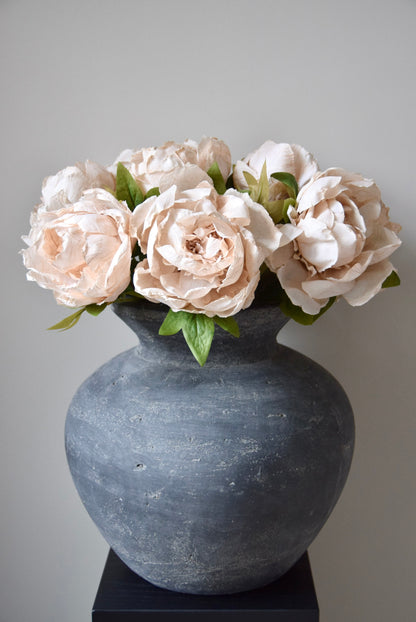 Grey vase with cream flowers on a grey background