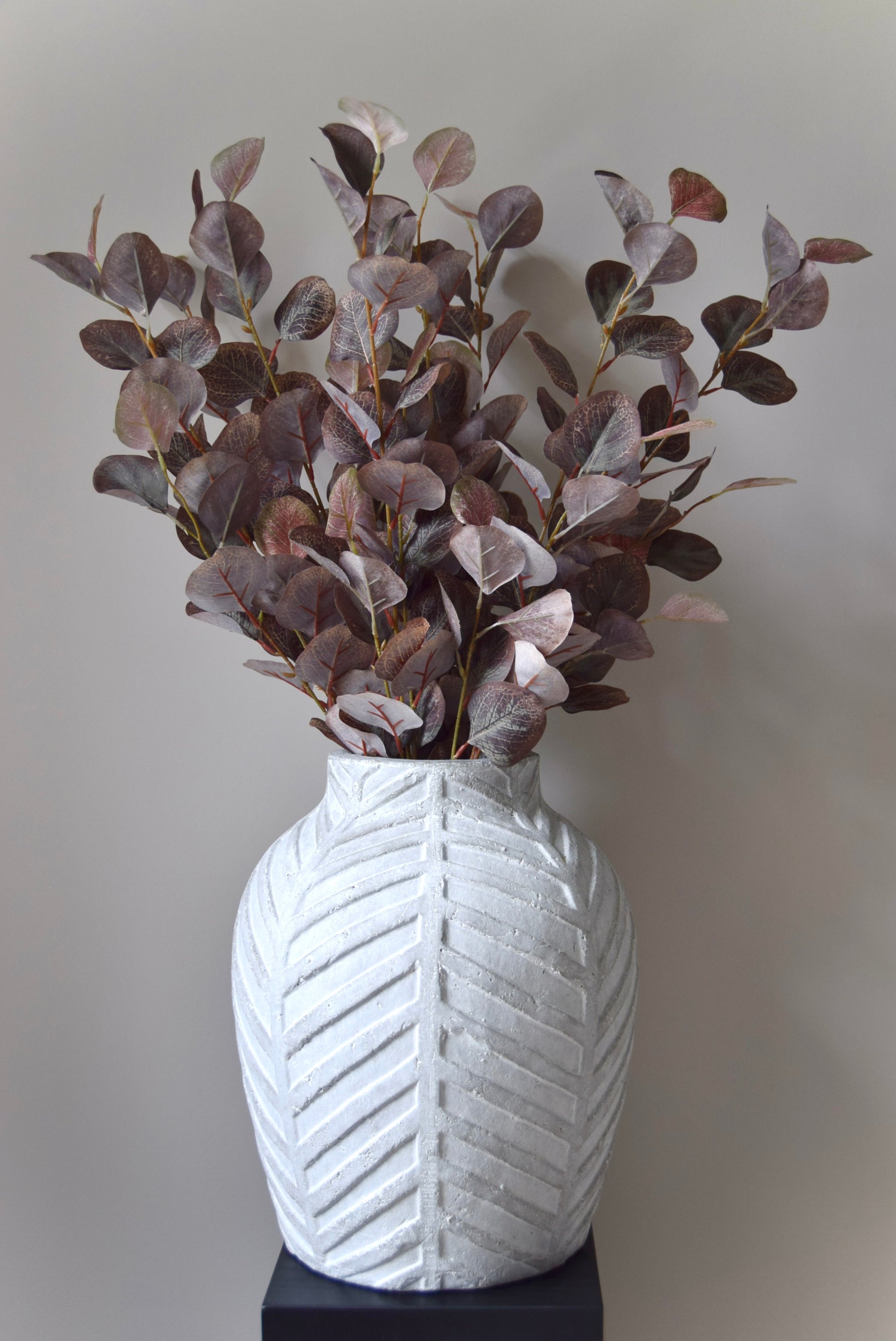 White textured vase with dried plants on a plain background
