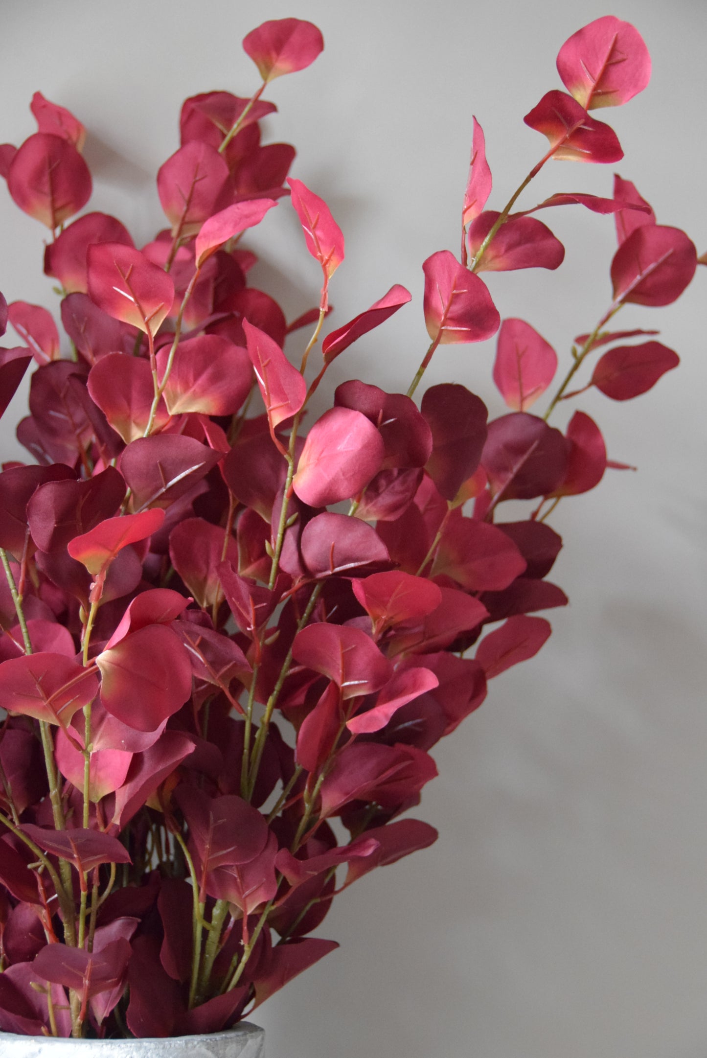 Bouquet of red artificial leaves on a light grey background
