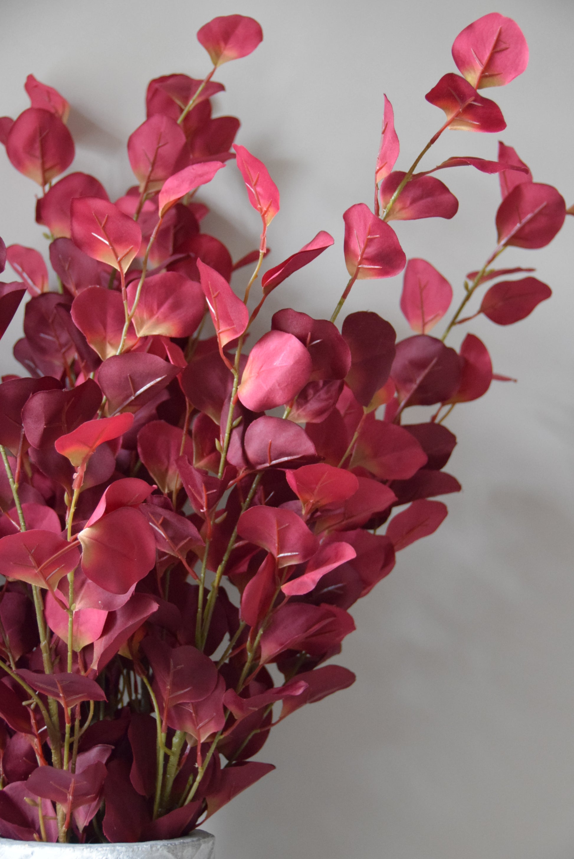 Bouquet of red artificial leaves on a light grey background