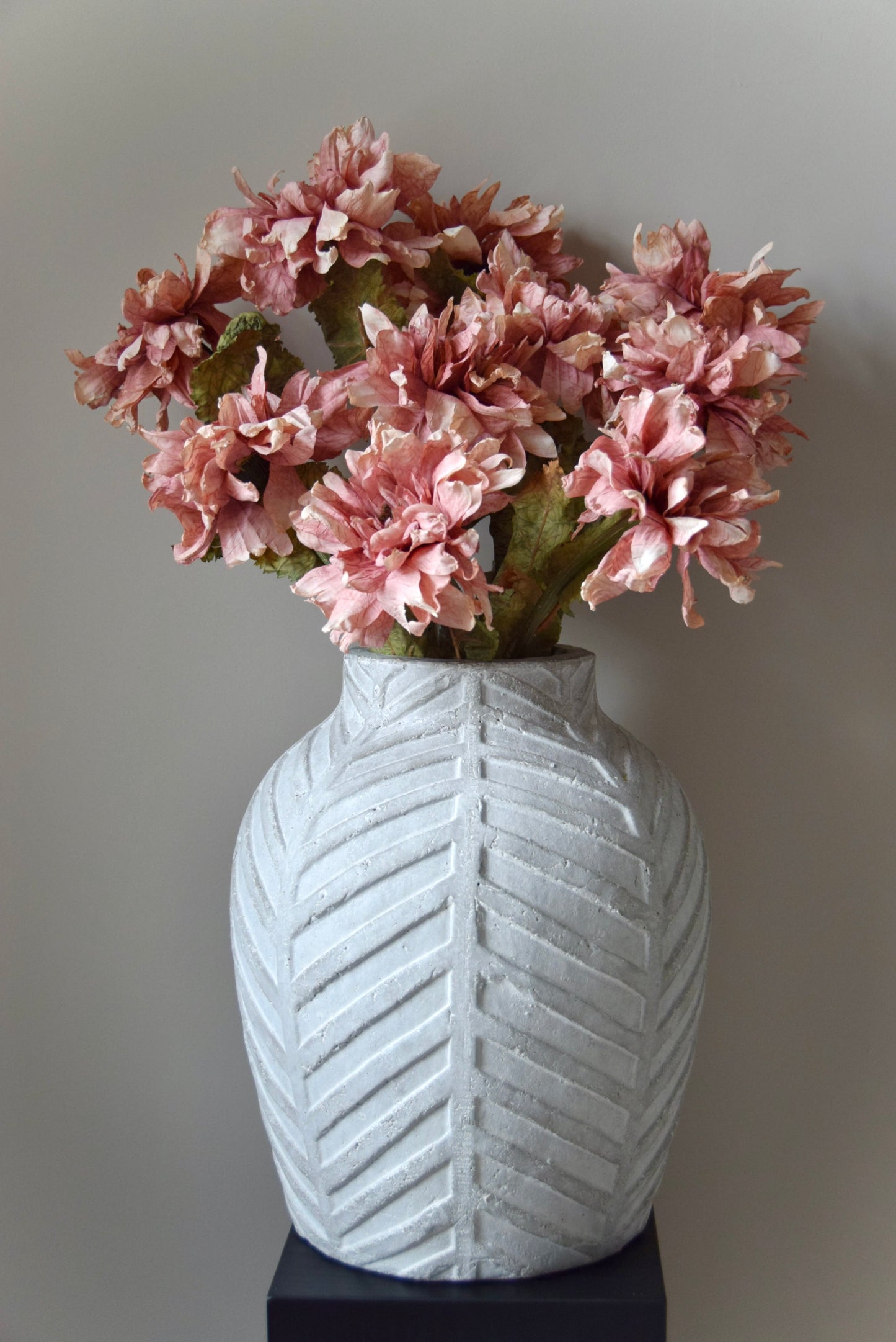 White textured vase with pink flowers against a plain background