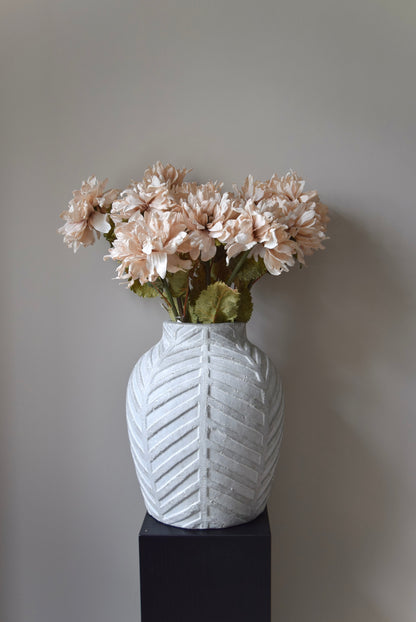 White textured vase with flowers against a plain background