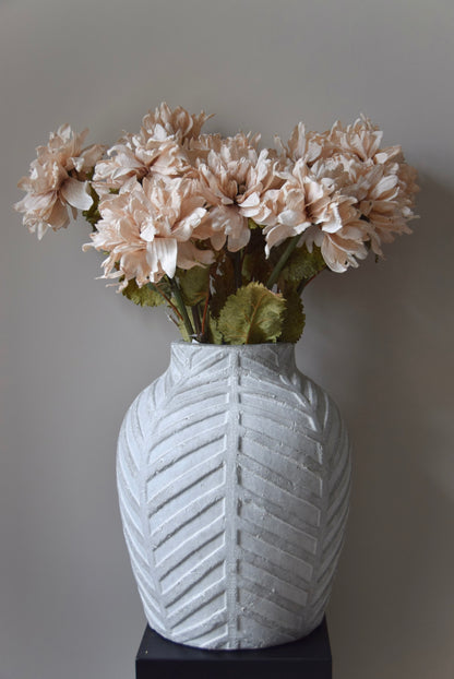White textured vase with beige flowers against a grey background