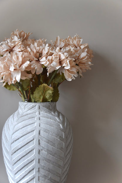 White textured vase with beige flowers against a plain background