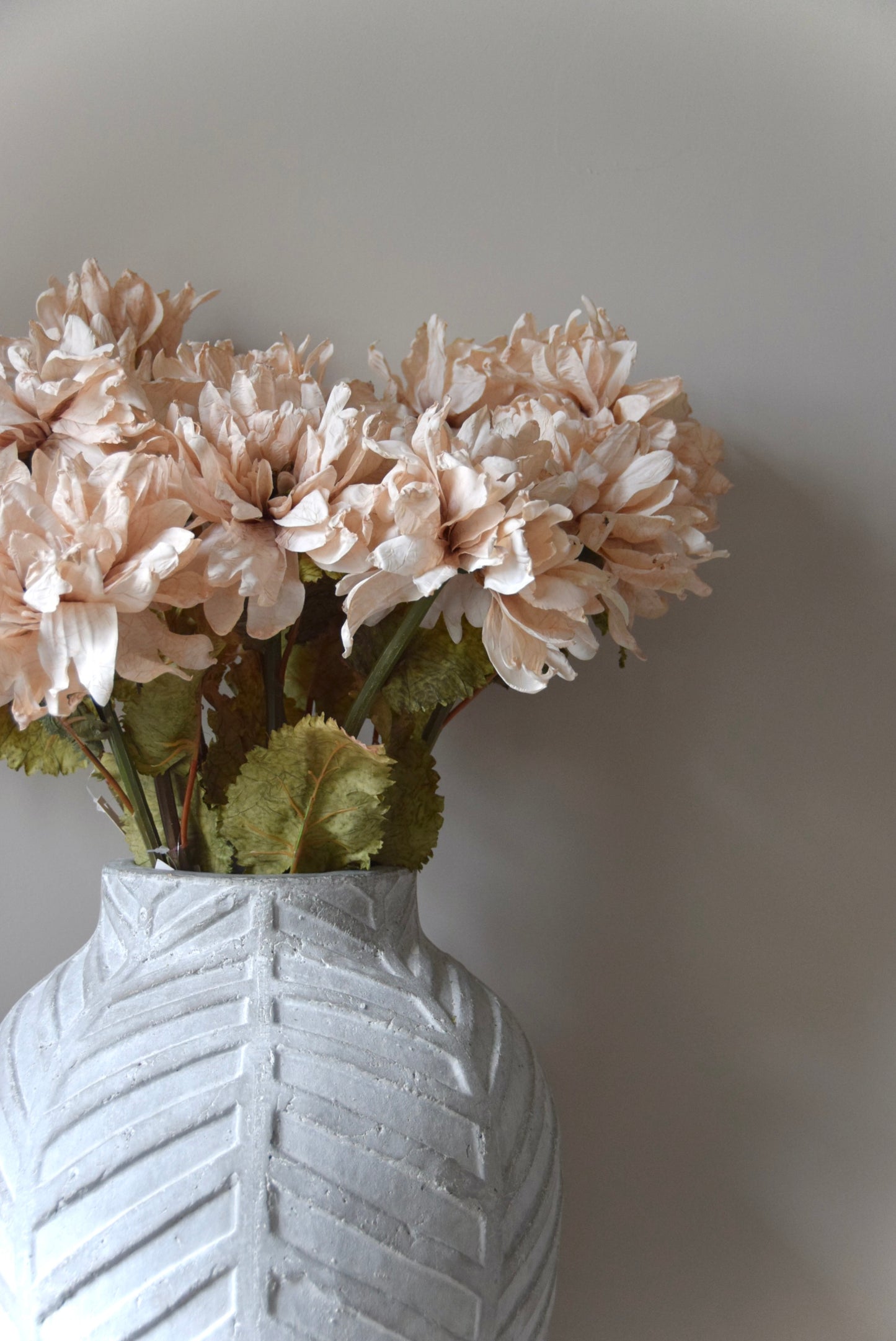 White textured vase with beige flowers against a plain background
