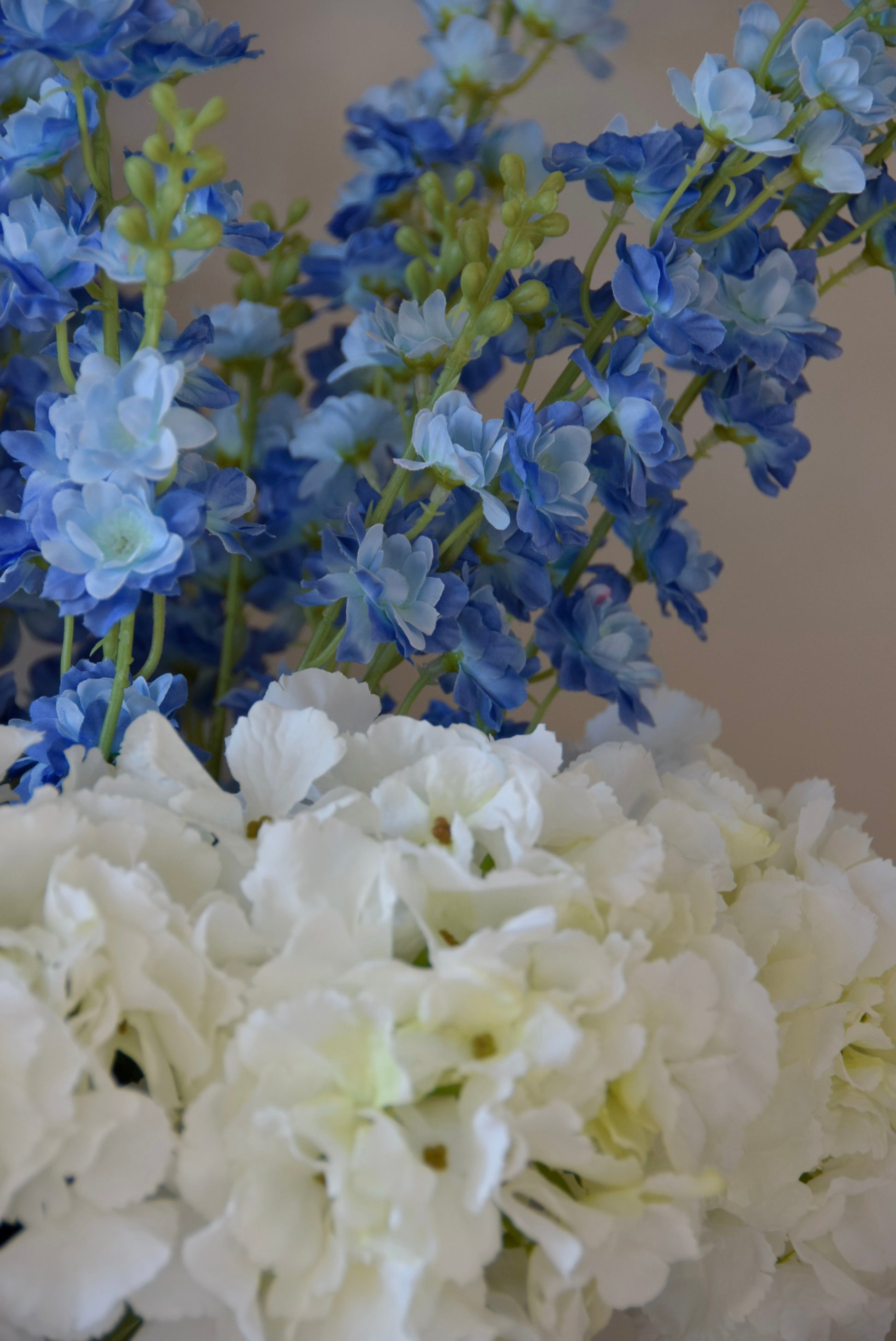 Close up of artificial white hydrangea and blue delphinium flower arrangement.
