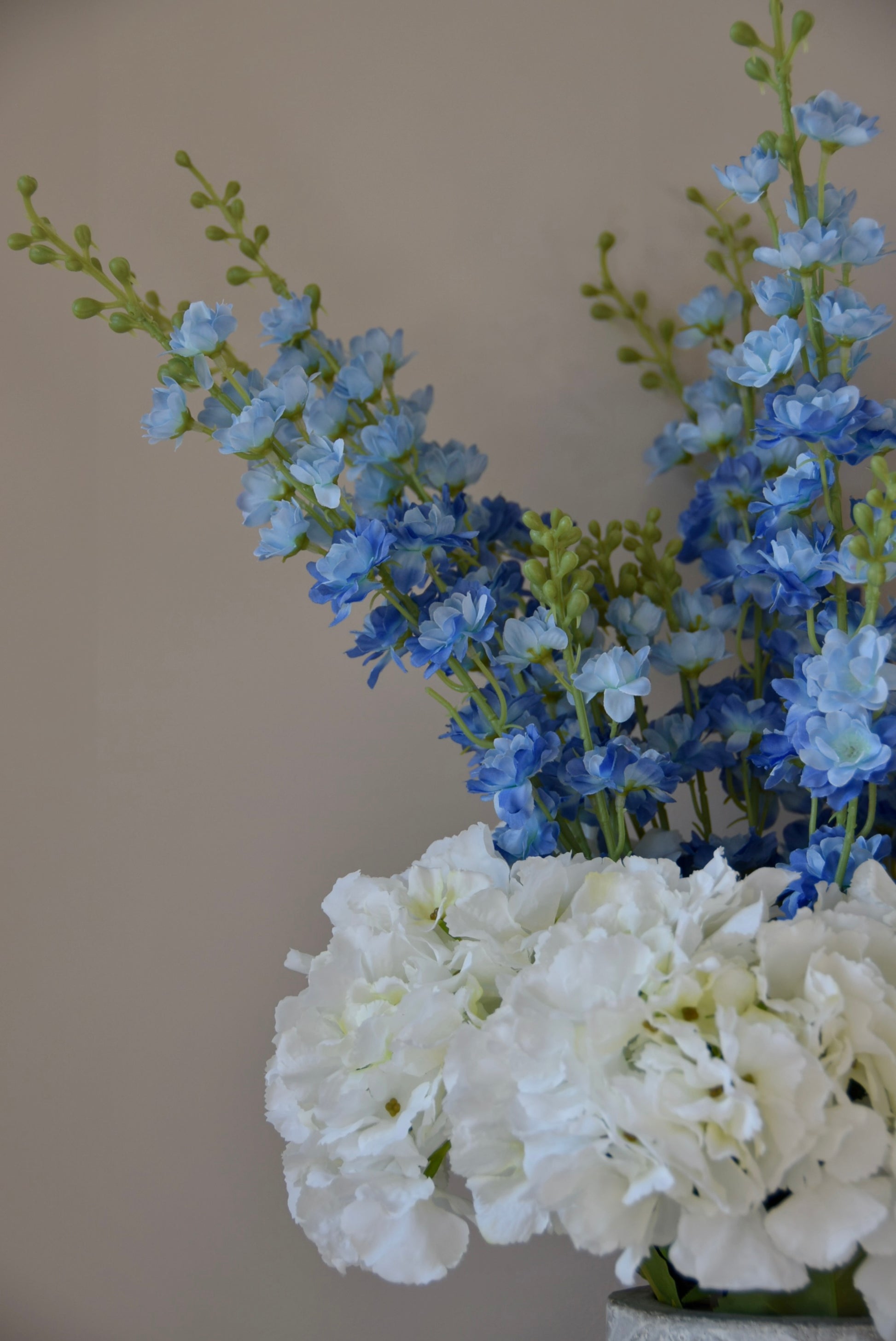 Close up of artificial white hydrangea and blue delphinium flower arrangement.