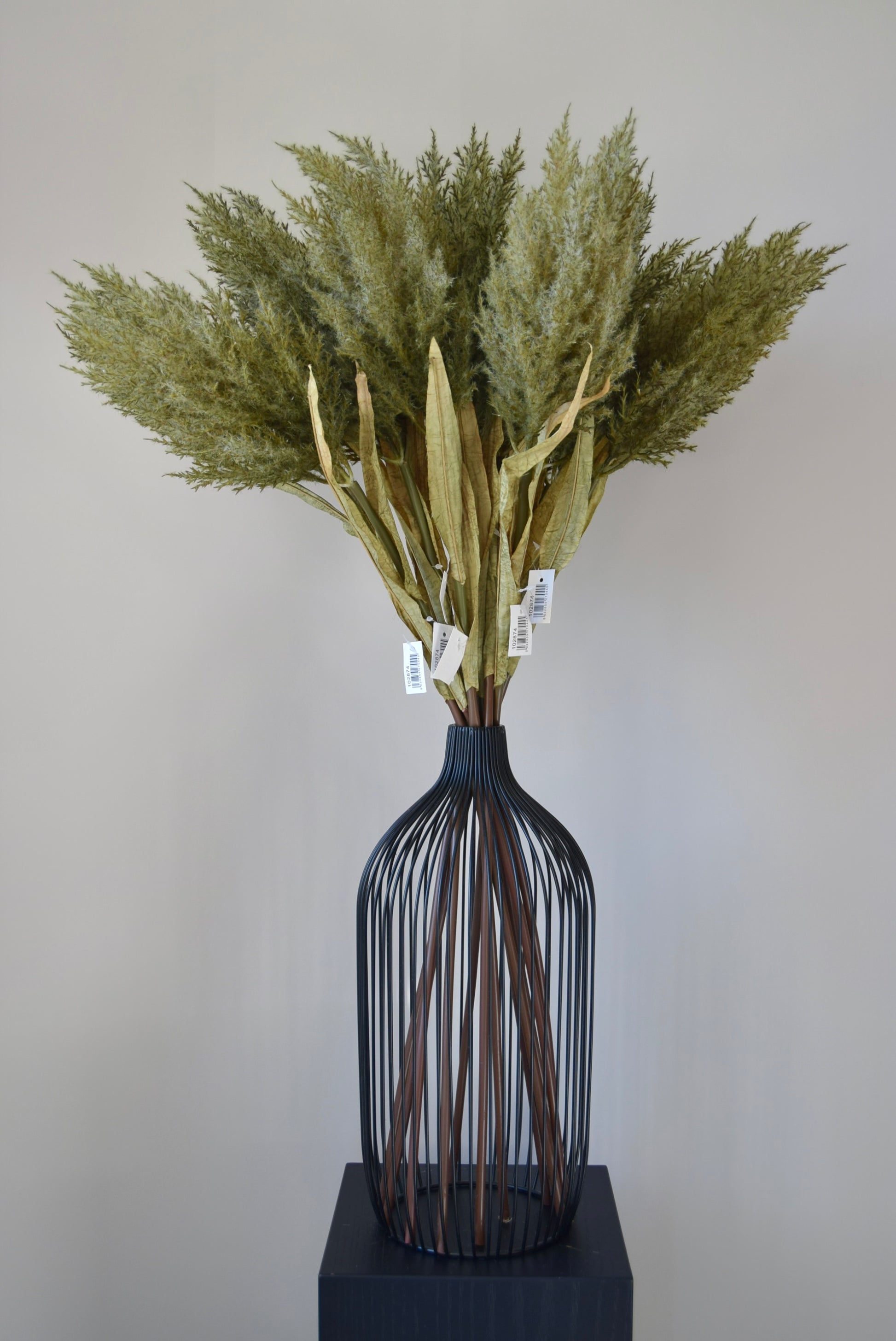 Decorative vase with dried plants on a plain background