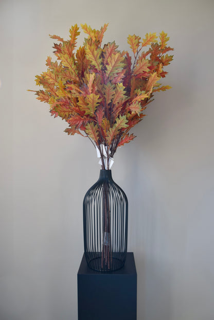 Decorative vase with autumn-themed leaves on a plain background