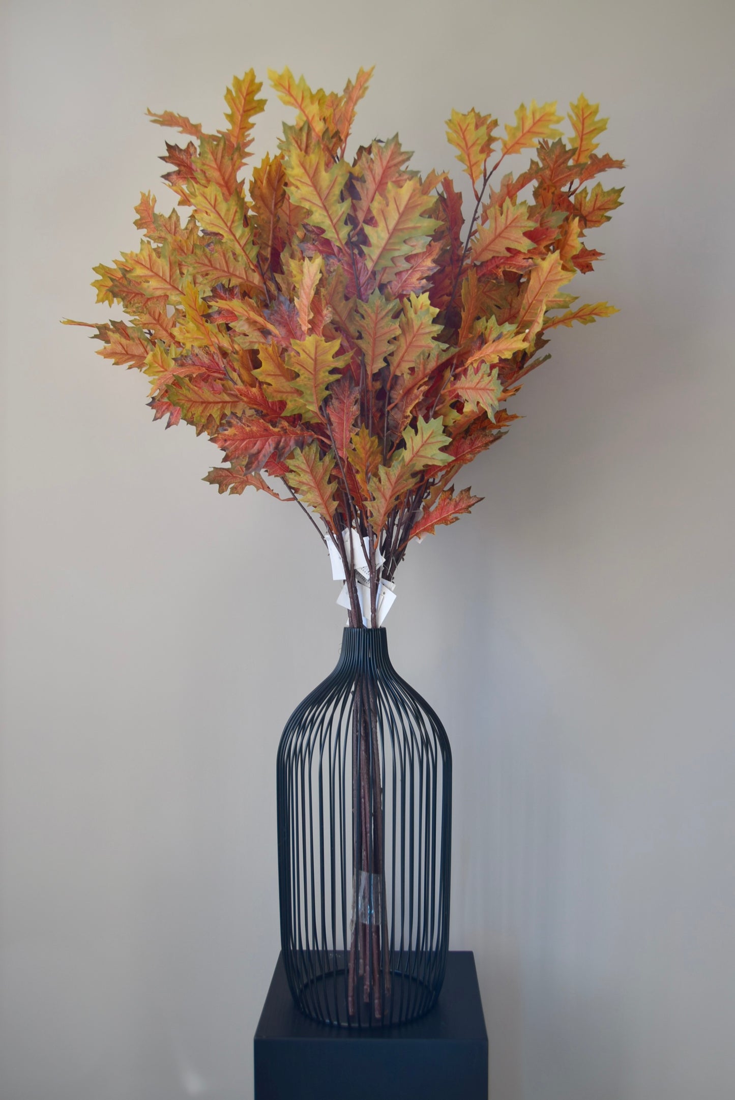 Decorative vase with autumn-themed leaves against a plain background