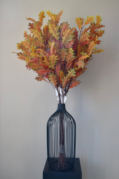 Decorative vase with autumn-themed leaves against a plain background