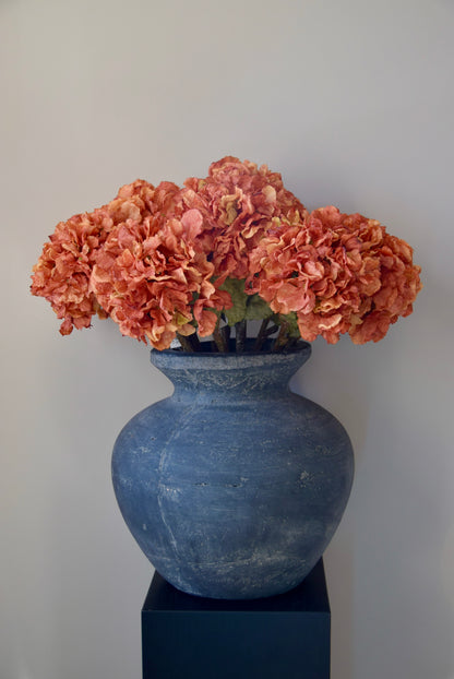 Grey vase with orange hydrangeas on a plain background