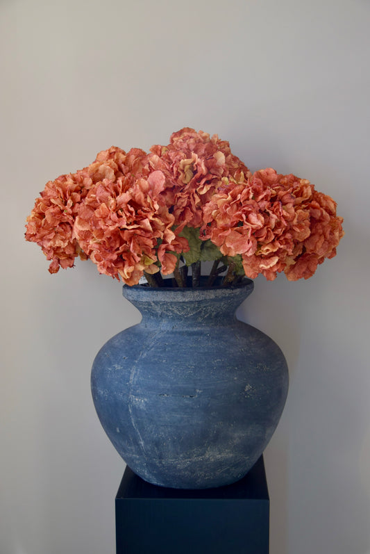 Grey vase with orange hydrangeas on a plain background