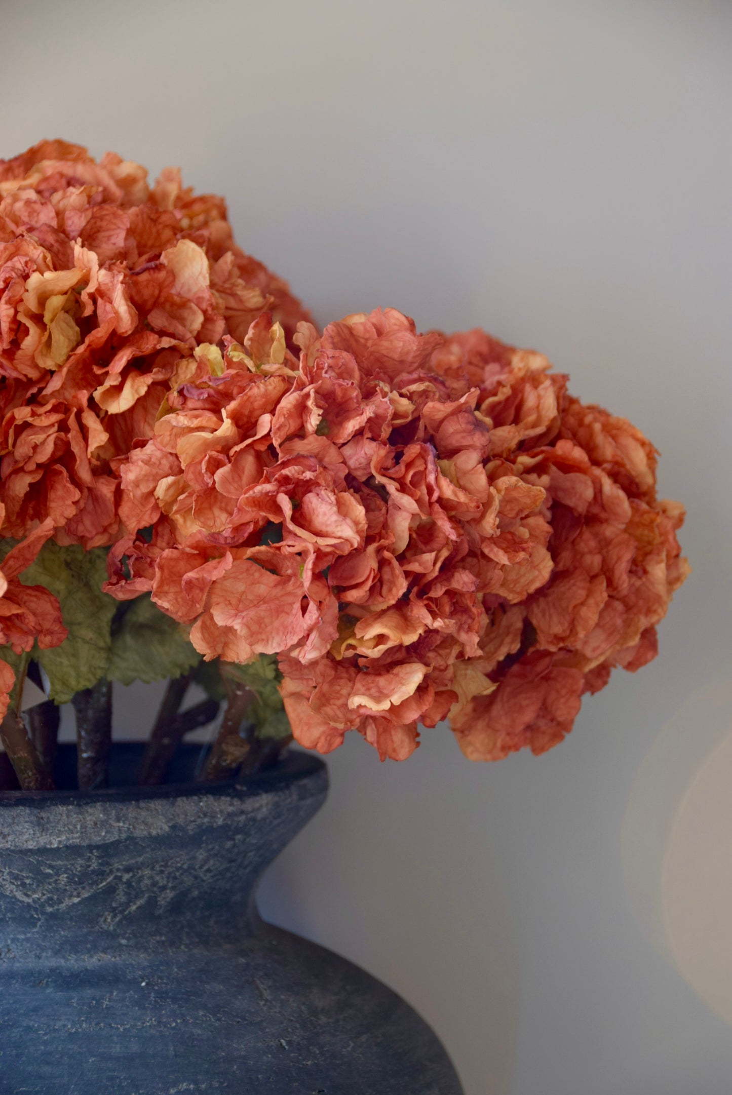 Decorative floral arrangement in a grey vase against a plain background
