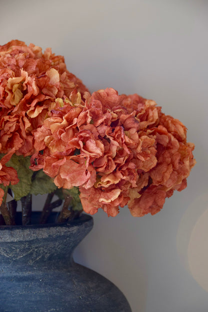 Decorative floral arrangement in a grey vase against a plain background