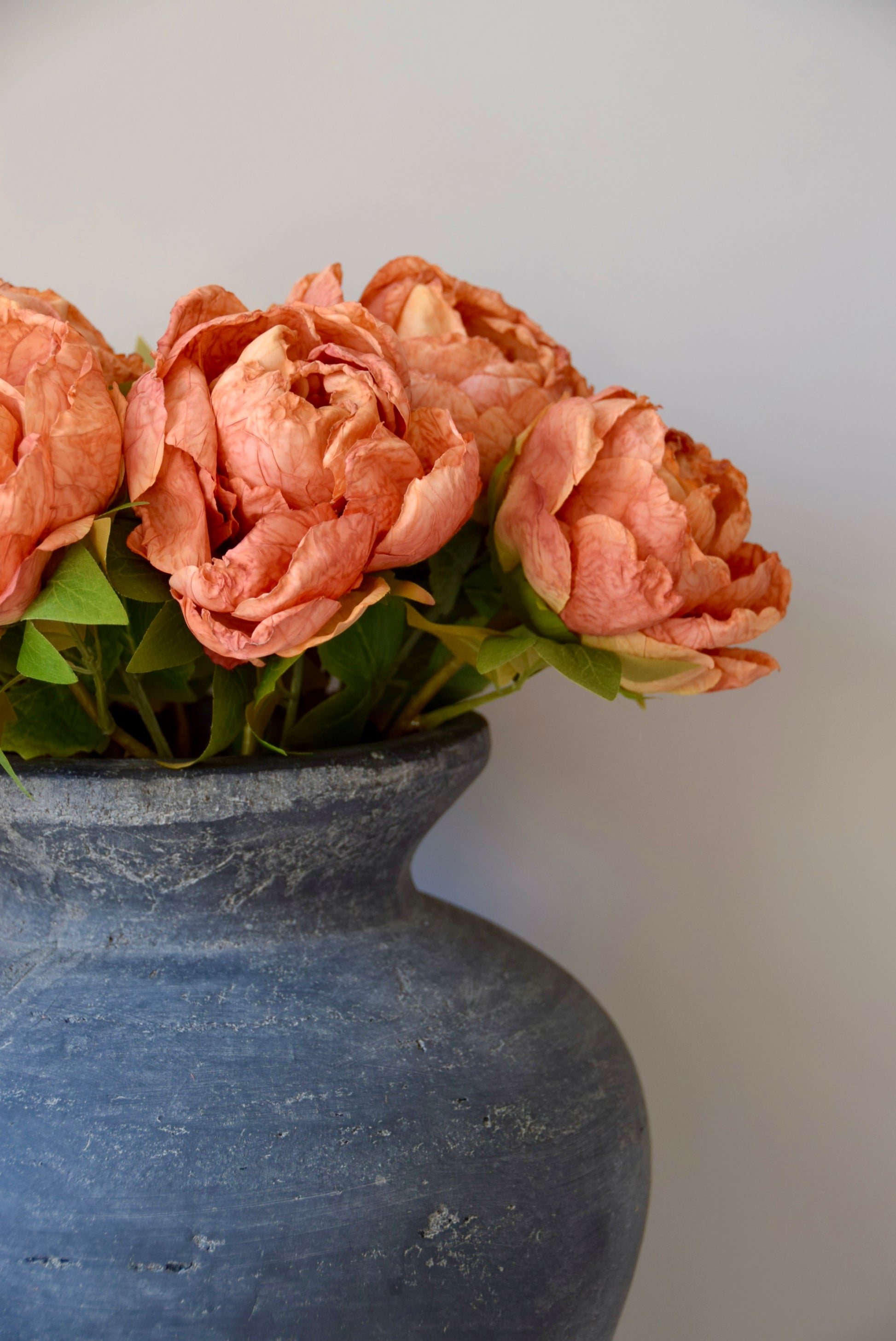 Decorative vase with orange flowers against a plain background