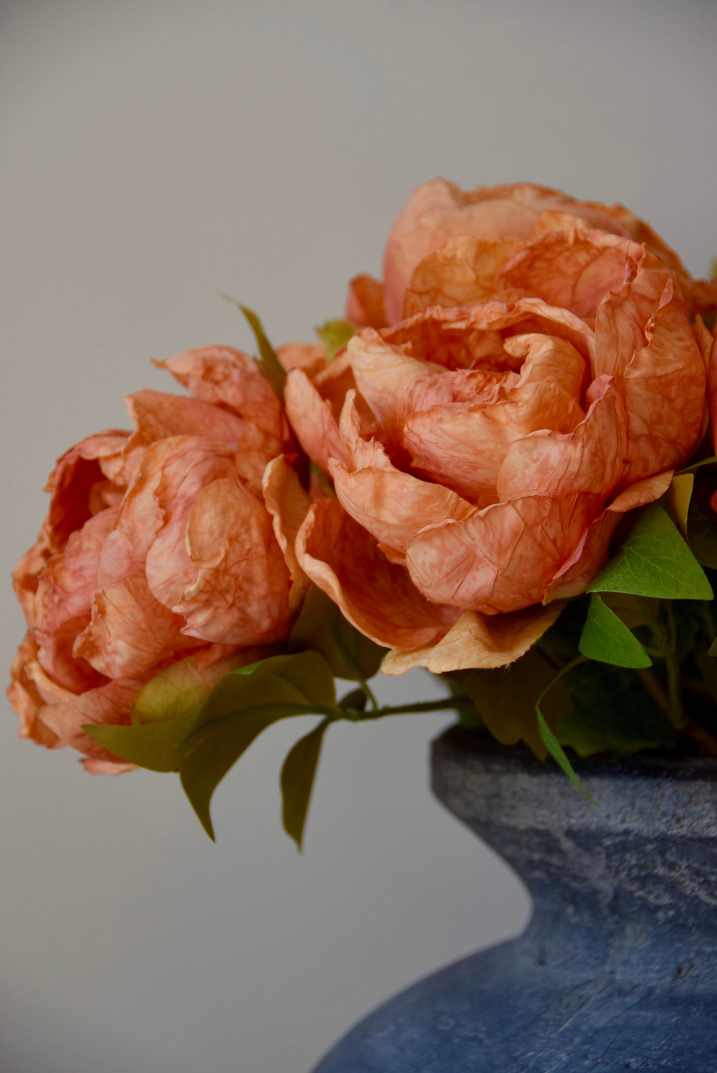 Close up of orange flowers in a dark grey vase.