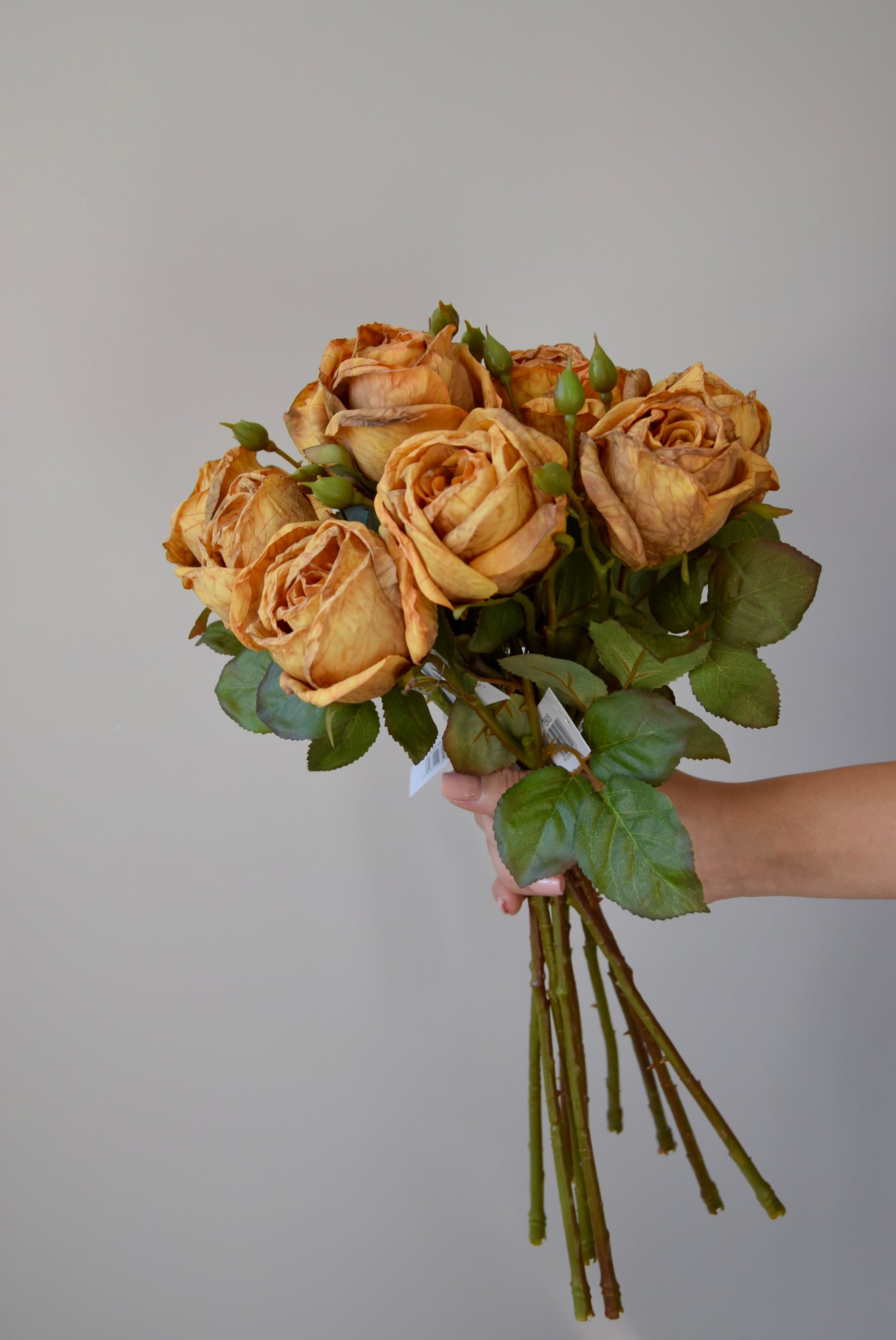 Bouquet of yellow roses held against a plain background